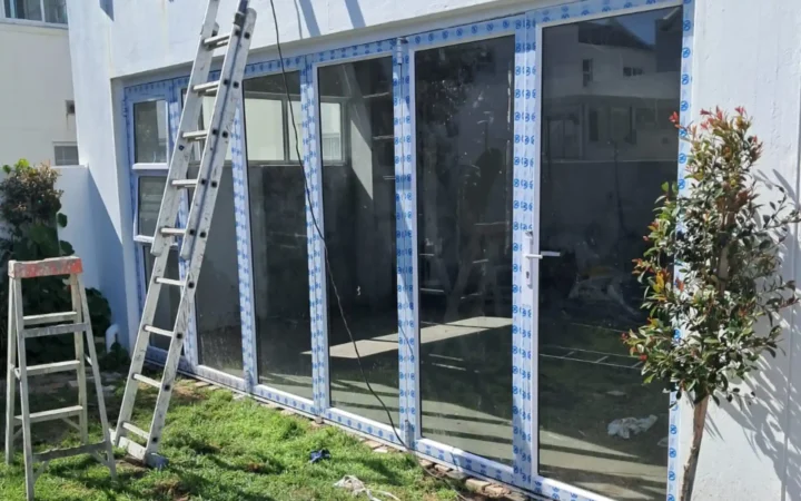 White aluminium folding doors with protective tape still on, fitted to a house in Camps Bay