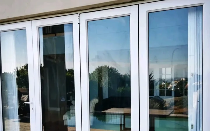 White aluminium stacking doors reflecting a swimming pool
