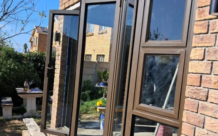 Bronze aluminium doors and windows with an opening sash, set in a face-brick wall