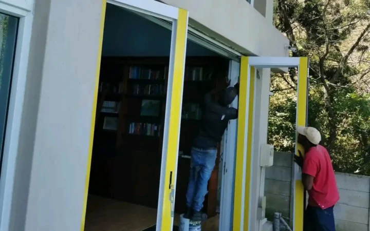 Installer fitting an aluminium hinged door with the frame still taped