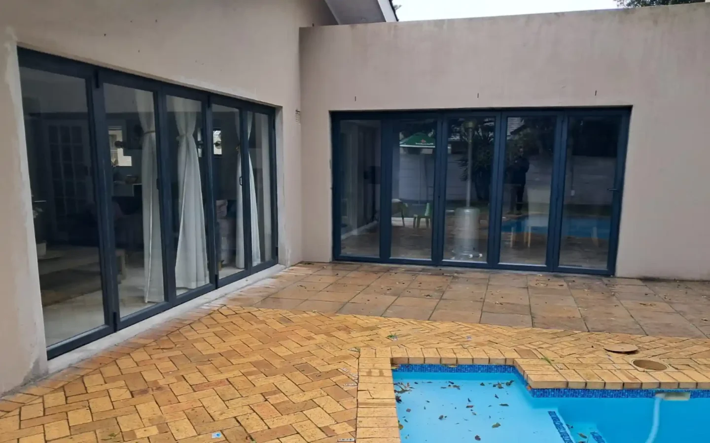 Two sets of charcoal aluminium folding doors facing a pool courtyard