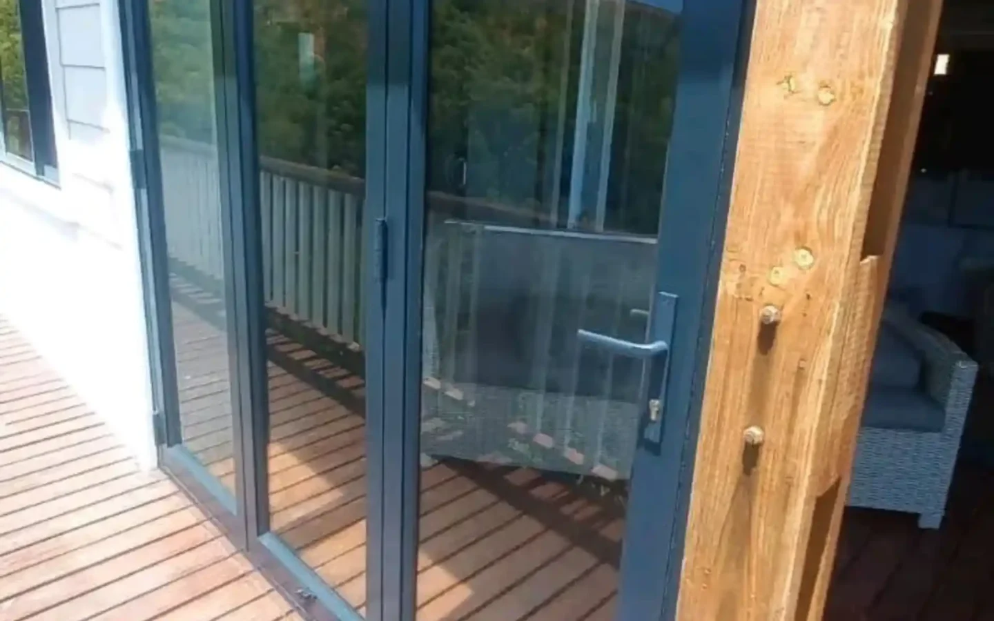 Charcoal aluminium stacking door opening onto a timber deck