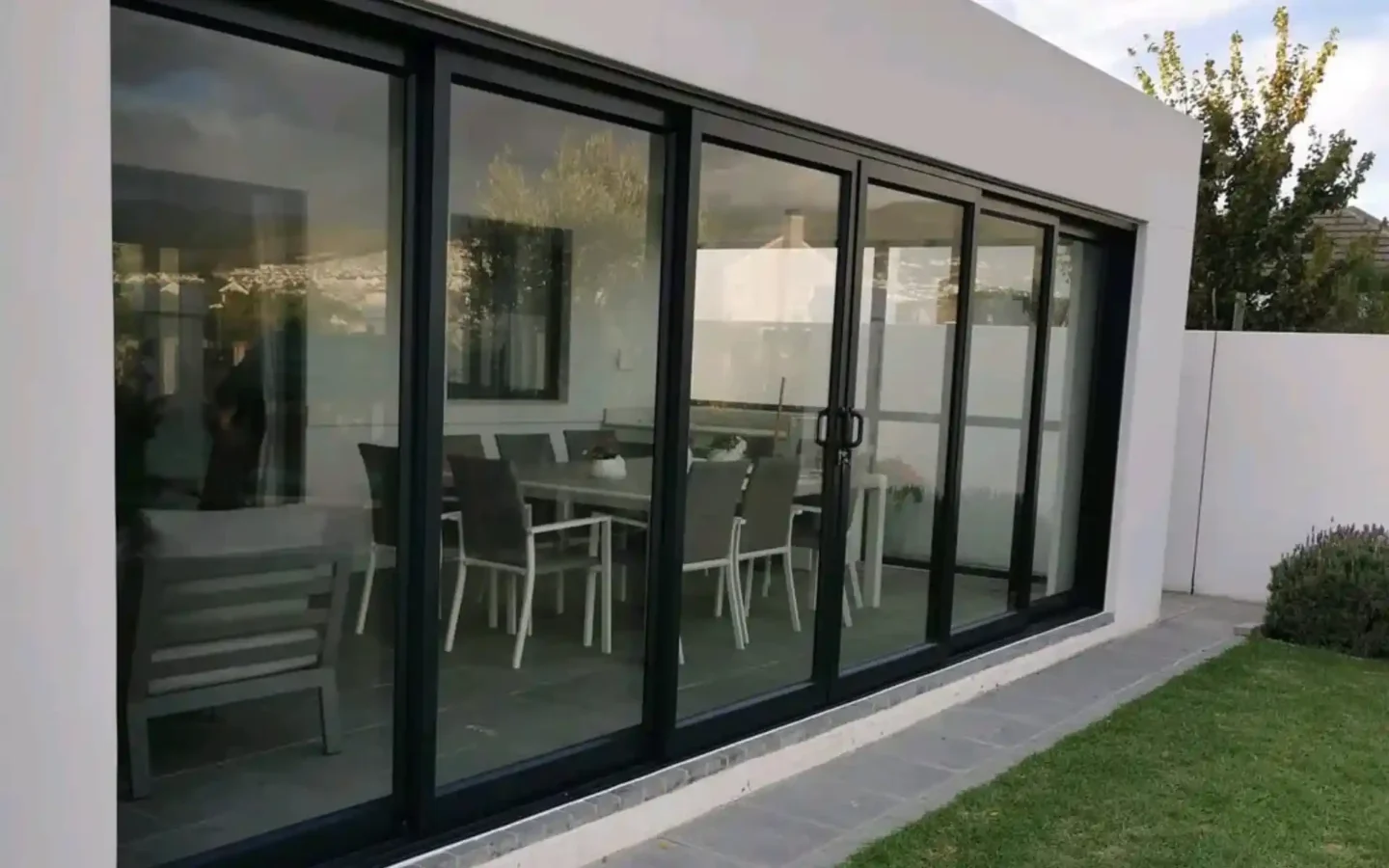 Black aluminium sliding doors across the full width of a dining room