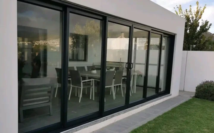 Black aluminium sliding doors across the full width of a dining room