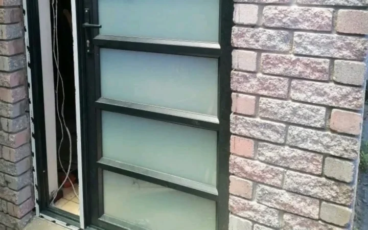 Charcoal aluminium door with obscure glass panels being installed