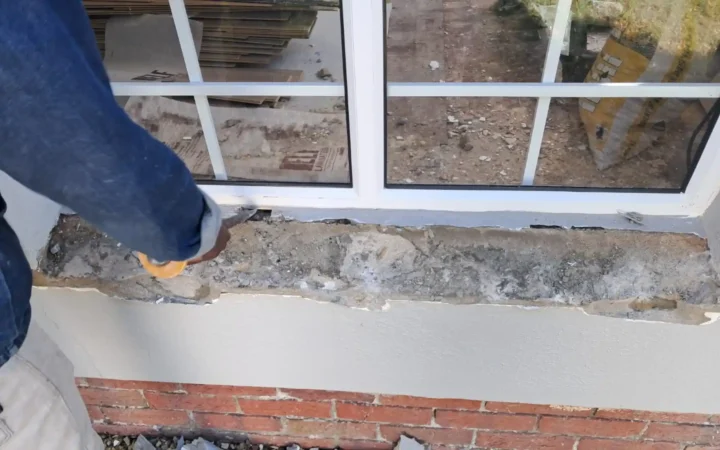 Installer making good the sill under a new white aluminium window