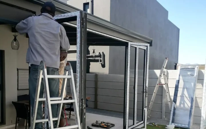 Installer on a ladder fixing the head of an aluminium door frame