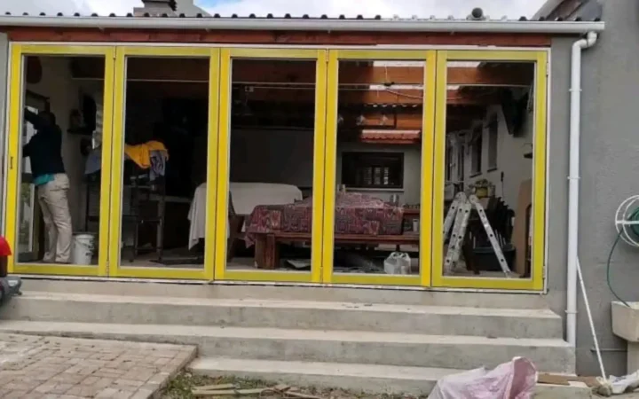 Aluminium folding doors with yellow protective tape, seen from the garden