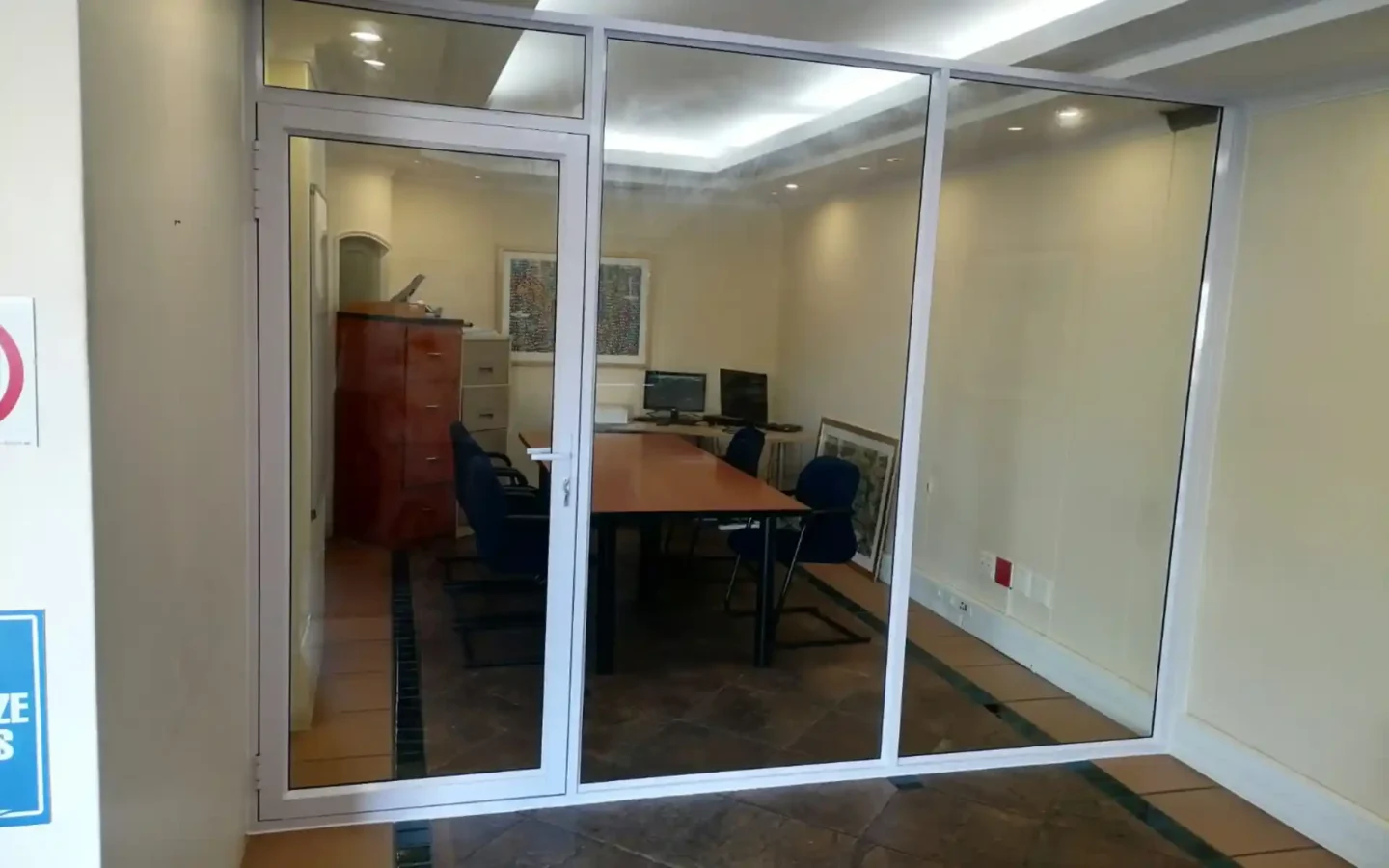 White aluminium glazed partition with a hinged door into an office