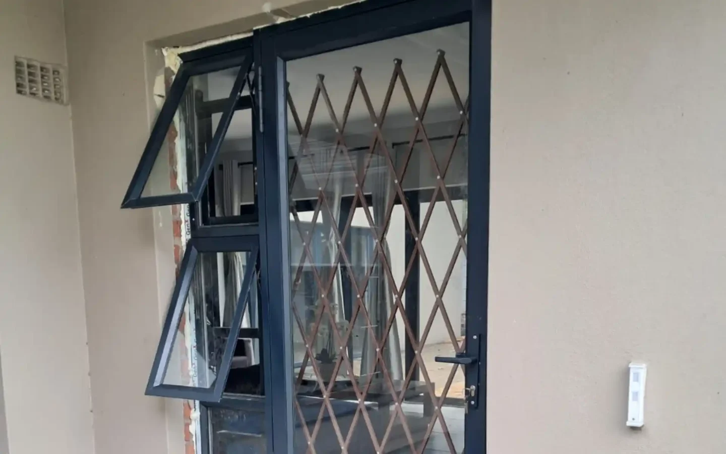 Charcoal top hung aluminium windows opened outward beside a trellis gate