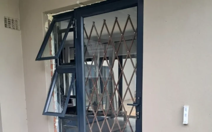 Charcoal top hung aluminium windows opened outward beside a trellis gate