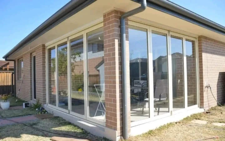 White aluminium sliding doors along both sides of a face-brick house