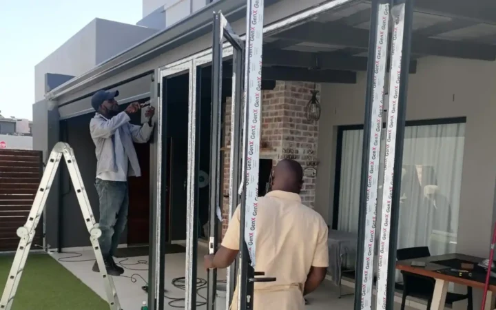 Two installers fitting aluminium doors at a house in Cape Town