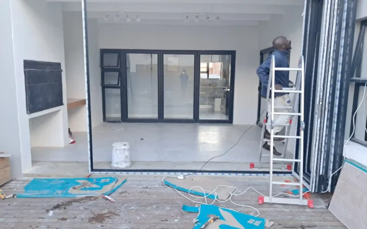 Installer on a ladder fitting aluminium sliding doors indoors