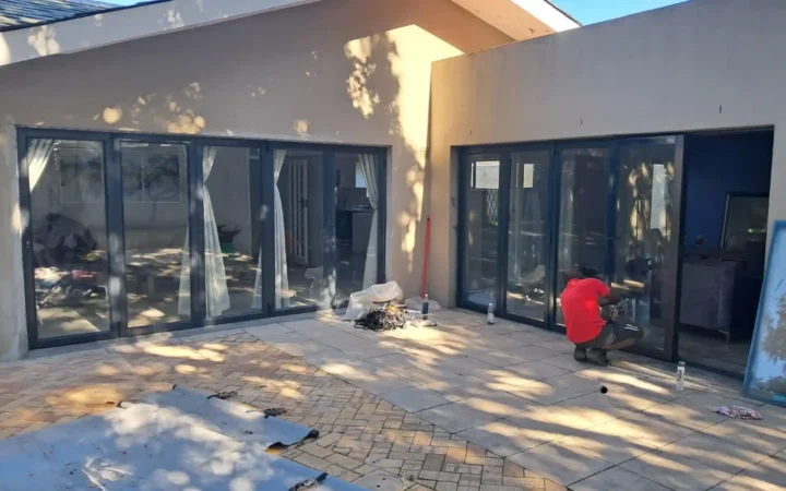 Installer fitting charcoal aluminium sliding doors to a patio