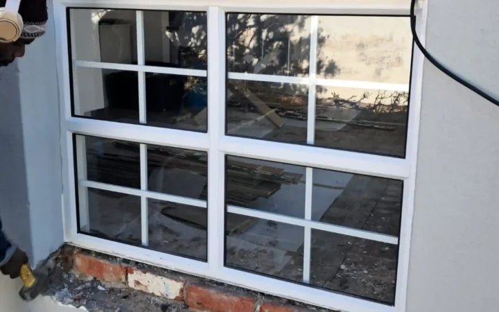 White aluminium windows with glazing bars fitted into a plastered wall