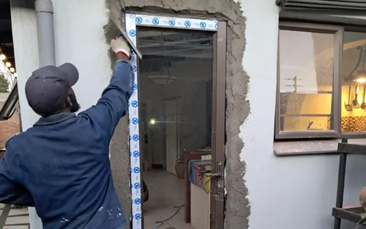 Installer plastering around an aluminium door frame after fitting