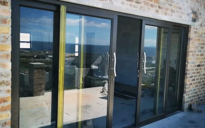 Black aluminium sliding doors being tested, with a sea view behind